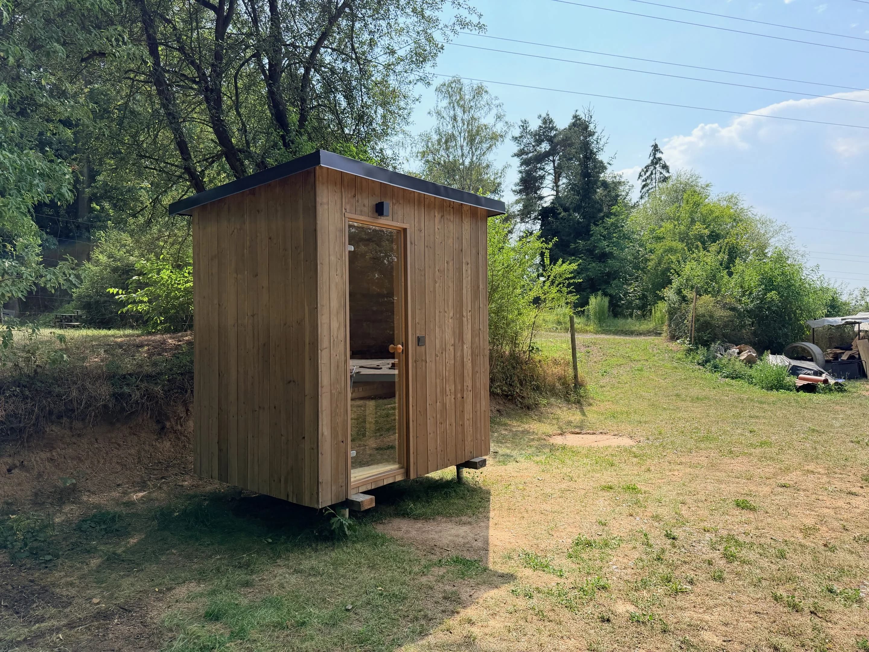 Hotová sauna v zahradě s modrým nebem, pohled z mírného podhledu